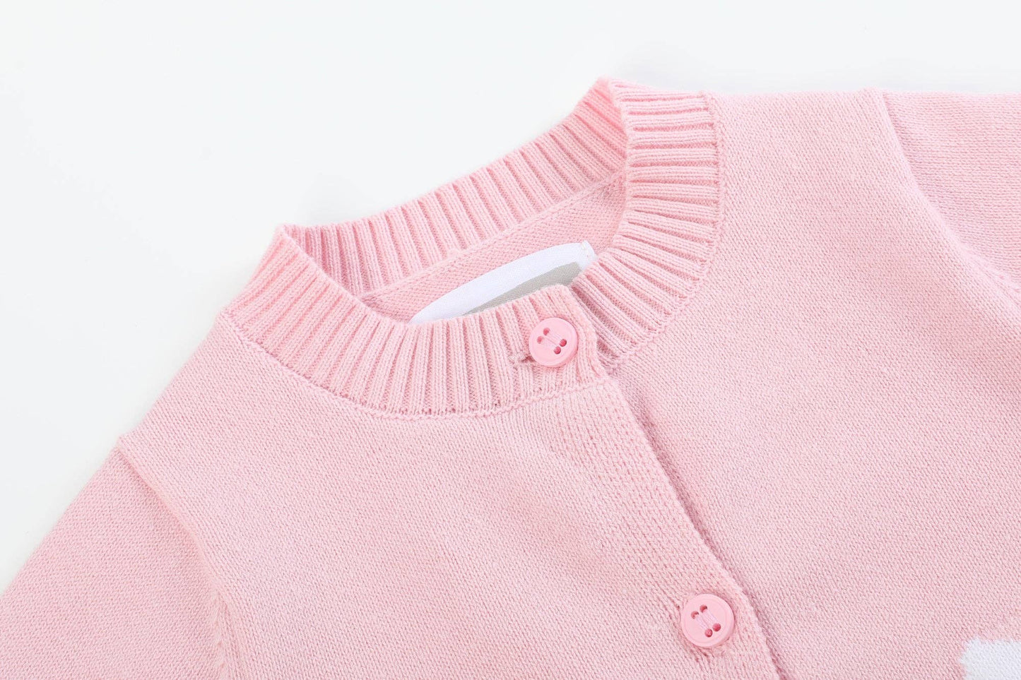 Close-up of a pink sweater with buttons on a white background