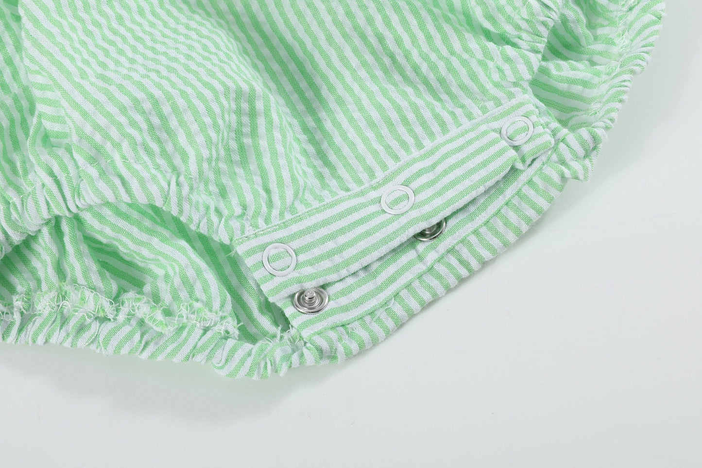 Green and white striped baby romper on a light gray background