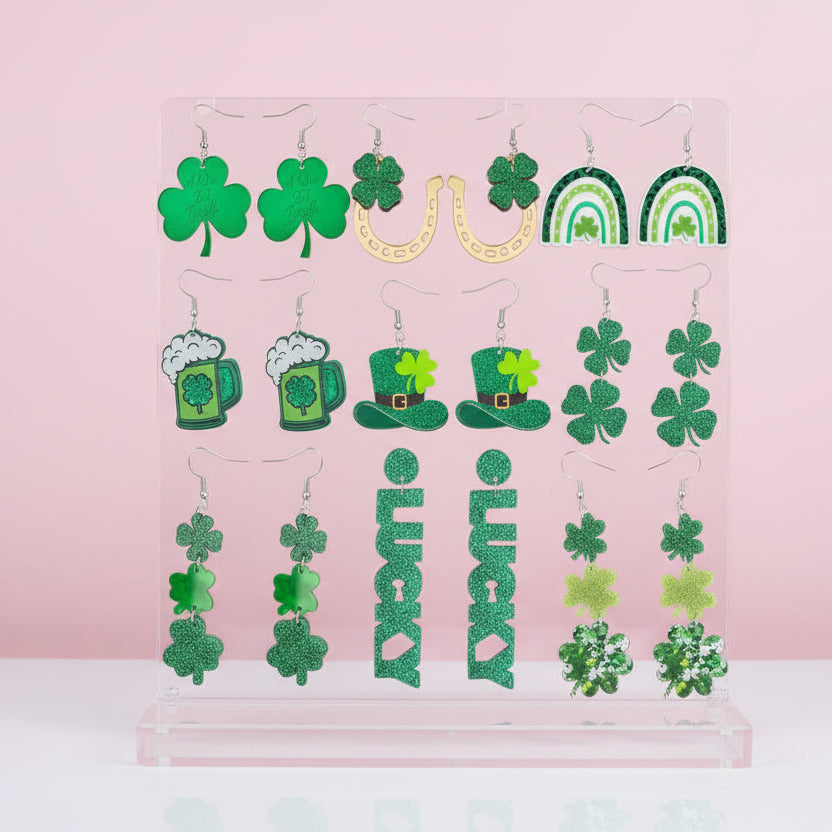 Collection of green-themed earrings on a pink background