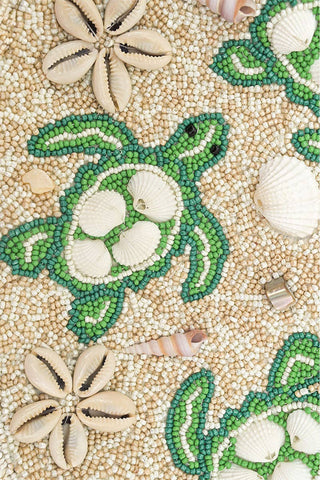 Mosaic artwork with turtle design and seashells on a textured background