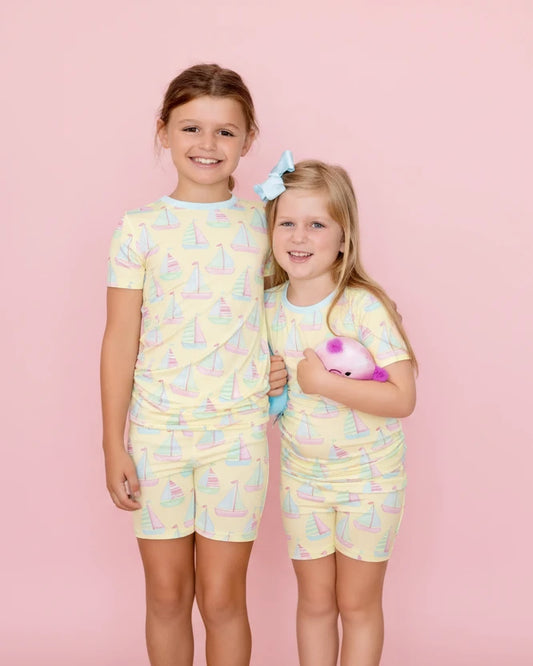 Two children wearing matching pajama sets with a pink background