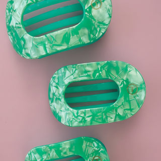 Green marbled hair clip on a pink background