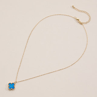 Gold necklace with a clover pendant on a light pink background