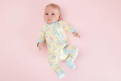 Baby wearing a colorful onesie with sailboats on a pink background