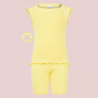 Yellow baby romper with ruffled trim and matching scrunchie on a pink background
