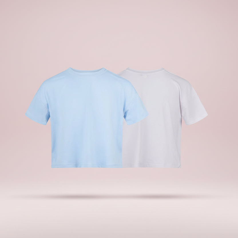Two crop tops, one light blue and one white, on a pink background
