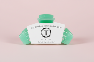 Green hair clip on a pink background