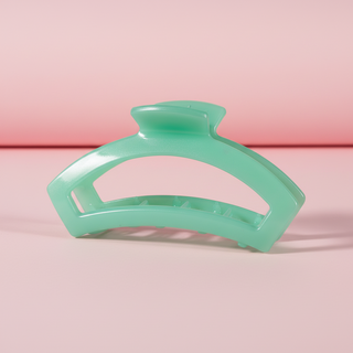 Green hair clip on a pink background