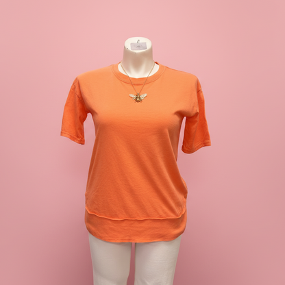 Orange t-shirt on a mannequin against a pink background