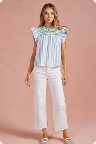Woman wearing a striped top and white pants on a pink background
