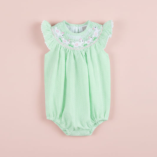 Green baby romper with floral embroidery on a pink background