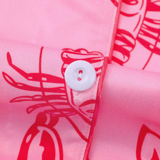 Close-up of pink fabric with red lobster patterns and a white button.