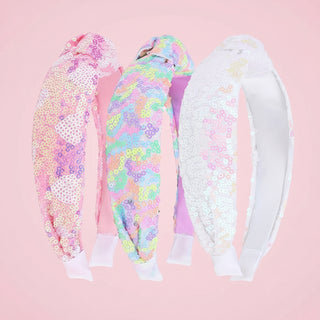 Three colorful headbands with sequin details on a pink background
