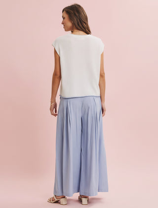 Woman wearing a white top and light blue skirt on a pink background