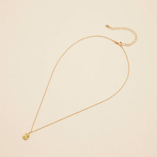 Gold Birthstone Pendant Necklace on a beige background. 