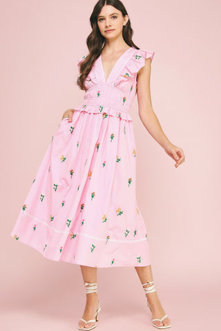 Woman wearing a pink floral dress against a pink background