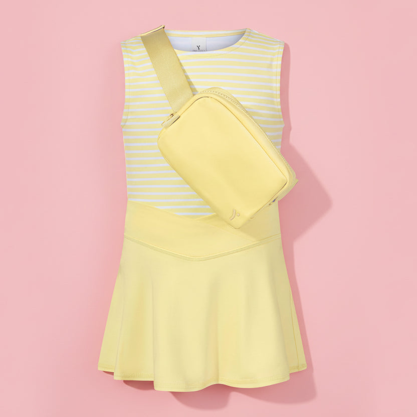 Yellow dress with a matching crossbody bag on a light pink background
