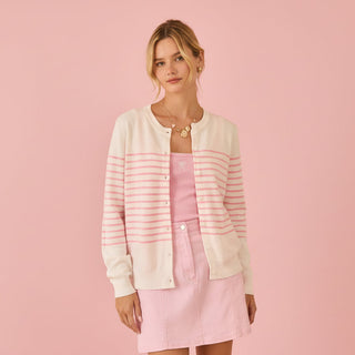 Woman wearing a pink and white striped cardigan over a pink dress on a pink background