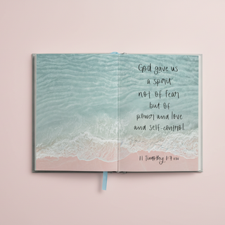 Open book with ocean scene and inspirational quote on a white background