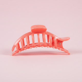 Coral-colored hair clip on a pink background