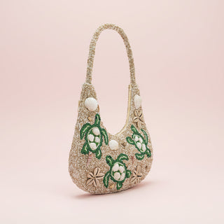 Handbag with green turtle designs on a light pink background
