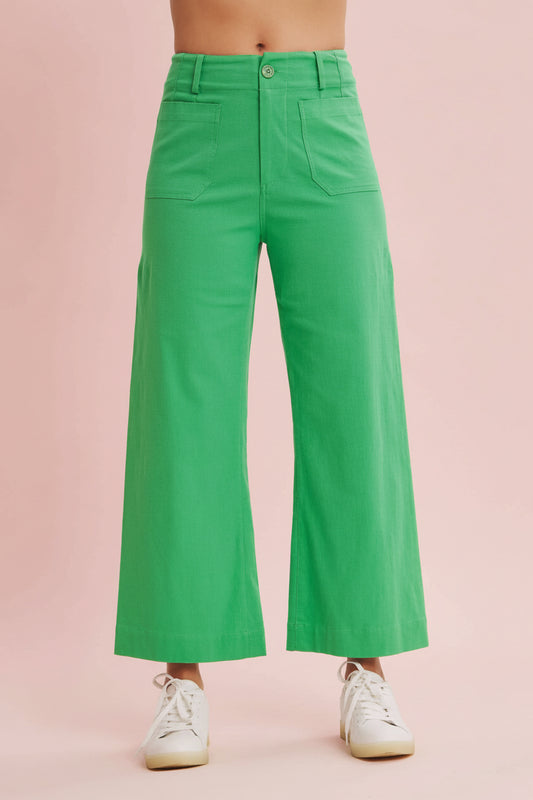 Green wide-leg pants worn by a person on a beige background