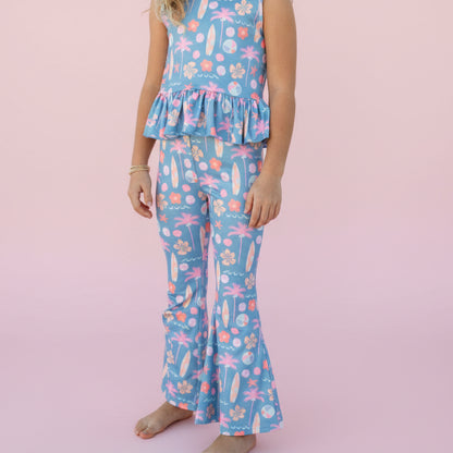 Girl wearing a blue floral outfit on a pink background.