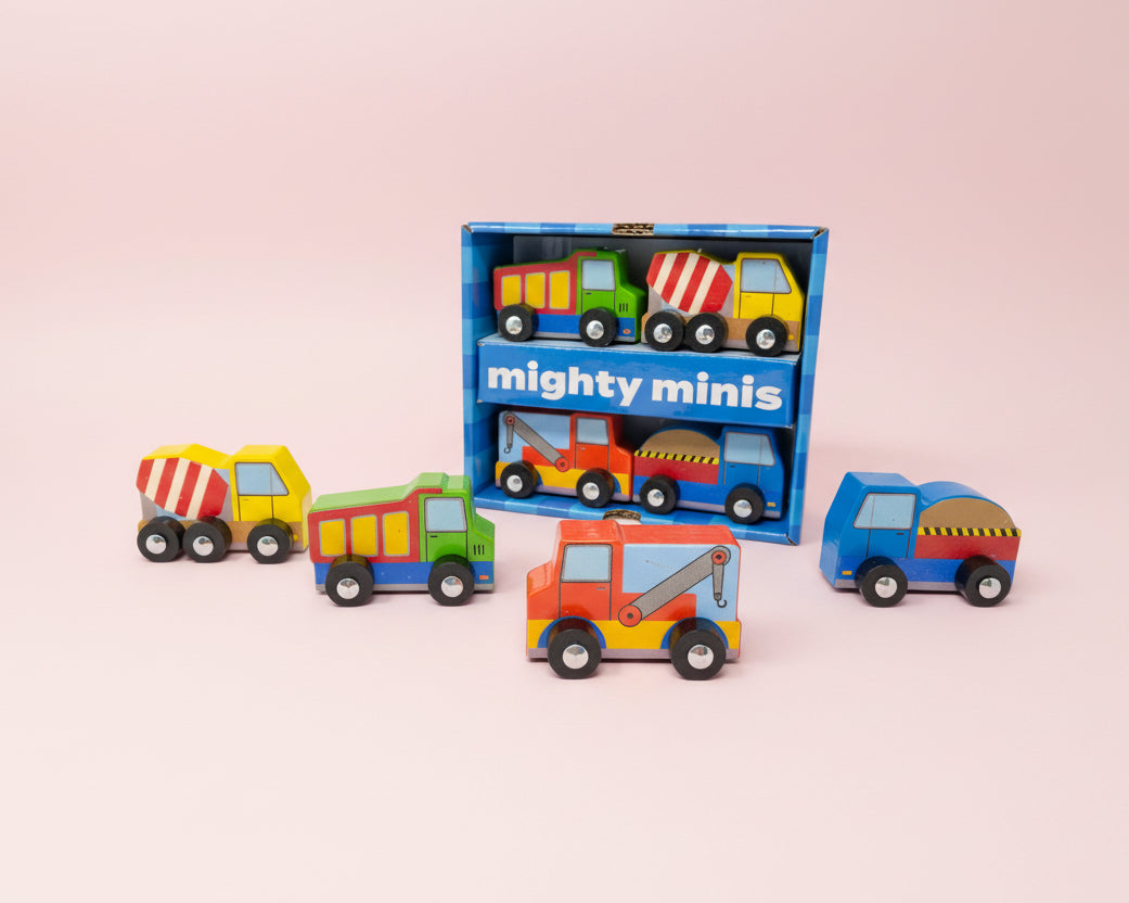 Set of colorful toy trucks in front of their packaging labeled 'mighty minis' on a pink background.
