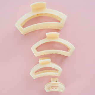 Set of beige hair clips arranged in a spiral on a light pink background