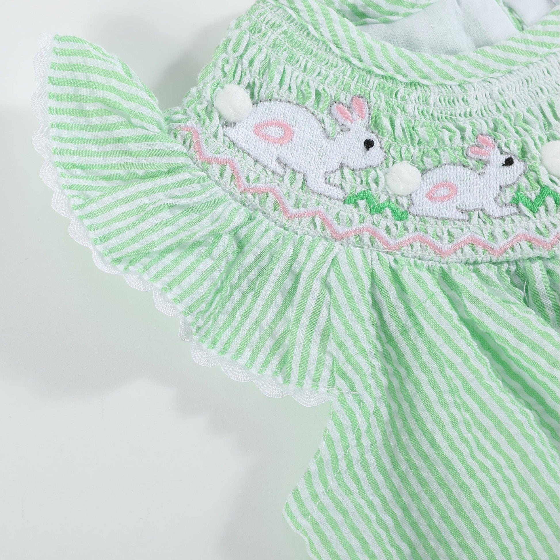 Green and white striped baby dress with embroidered bunnies on a white background