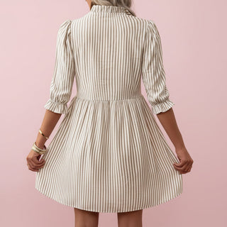 Woman wearing a striped dress against a pink background