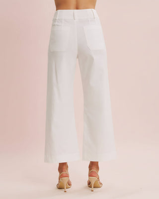 White pants worn by a person on a pink background