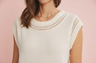 Woman wearing a light-colored sleeveless top against a pink background