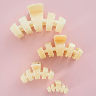 Set of beige hair clips arranged on a light pink background