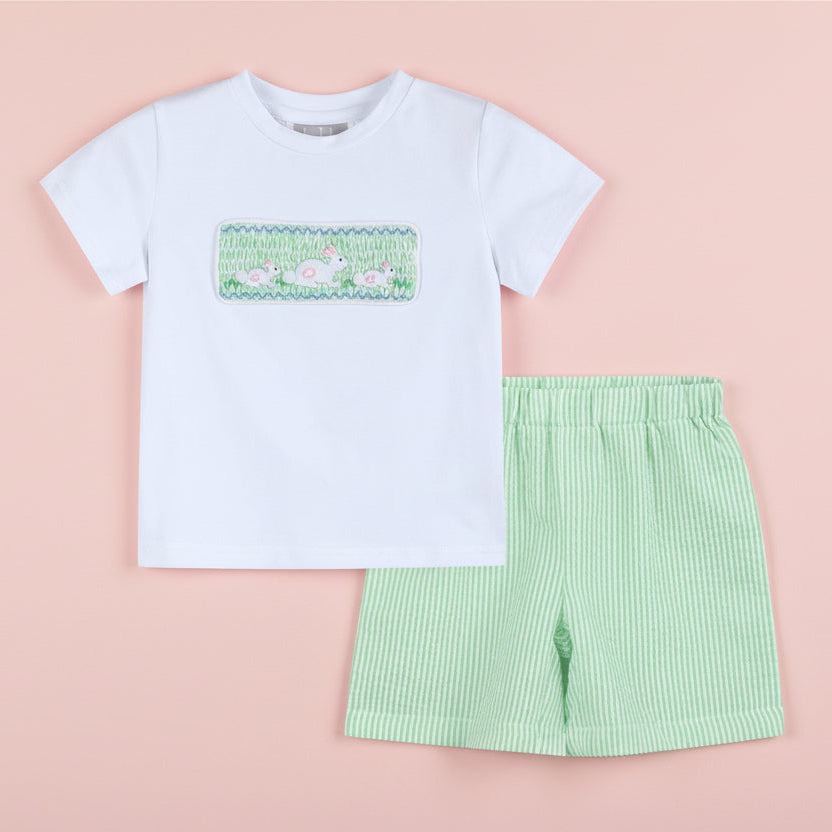 Children's outfit with white t-shirt and green shorts on a pink background