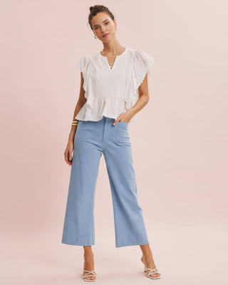 Woman wearing a white blouse and light blue pants on a pink background