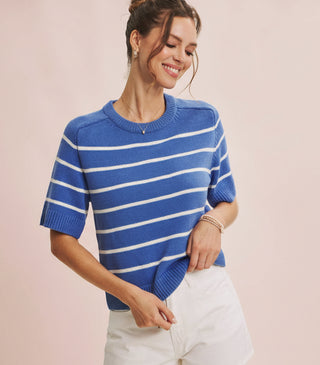 Woman wearing a blue and white striped sweater against a light pink background