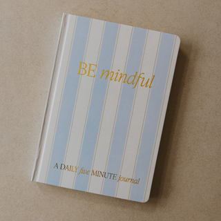 Journal with blue and white striped cover and 'BE mindful' text on a beige background