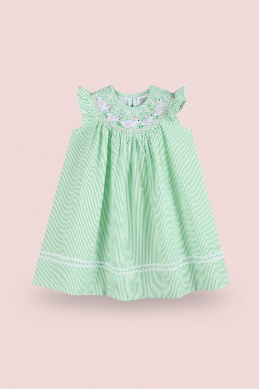 Green dress with white embroidery on a pink background