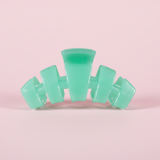 Green hair clip on a pink background