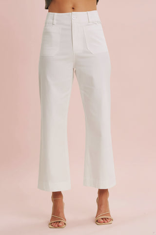 White pants worn by a person on a beige background