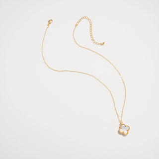 Gold necklace with a clover pendant on a light pink background