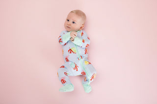 Baby wearing a colorful onesie with a hermit crab pattern on a pink background