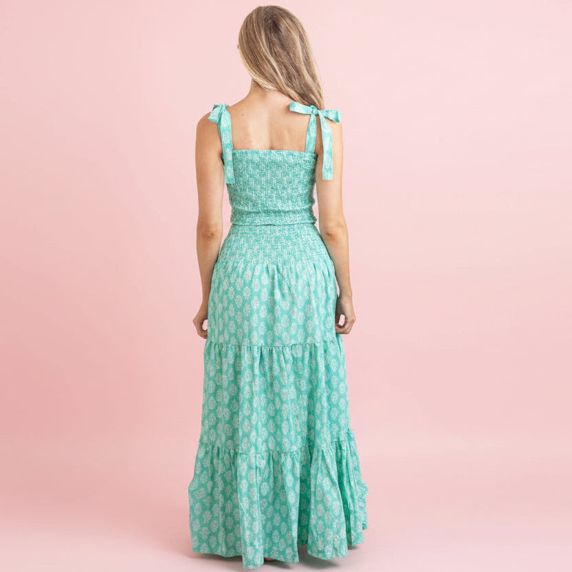 Woman wearing a green dress with a floral pattern on a pink background