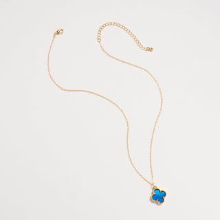 Gold necklace with a clover pendant on a light pink background