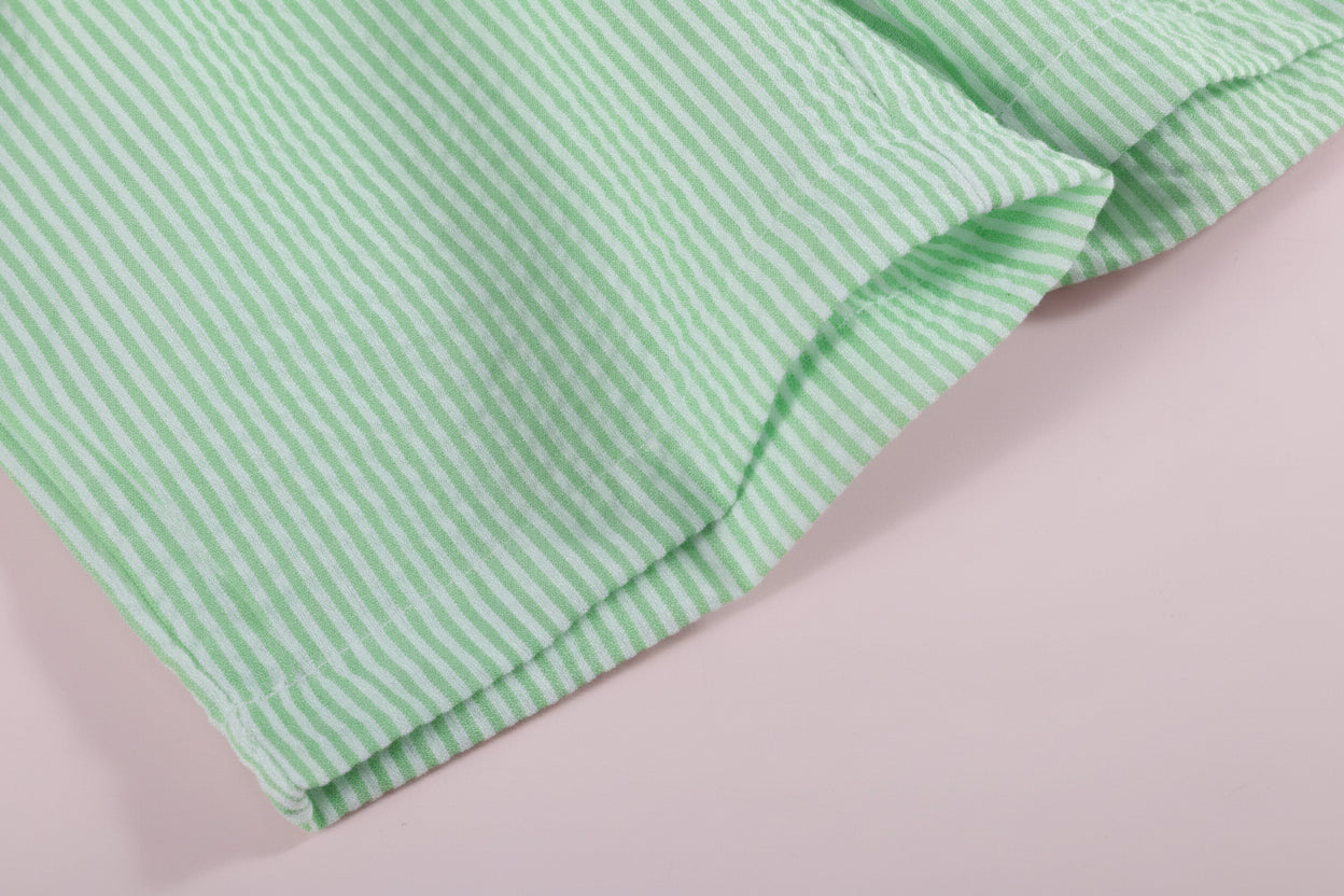 Green and white striped fabric on a light pink background