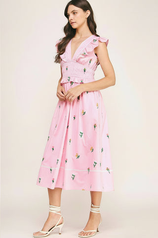 Woman wearing a pink floral dress on a plain background