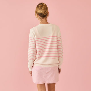 Person wearing a striped sweater and pink skirt on a pink background