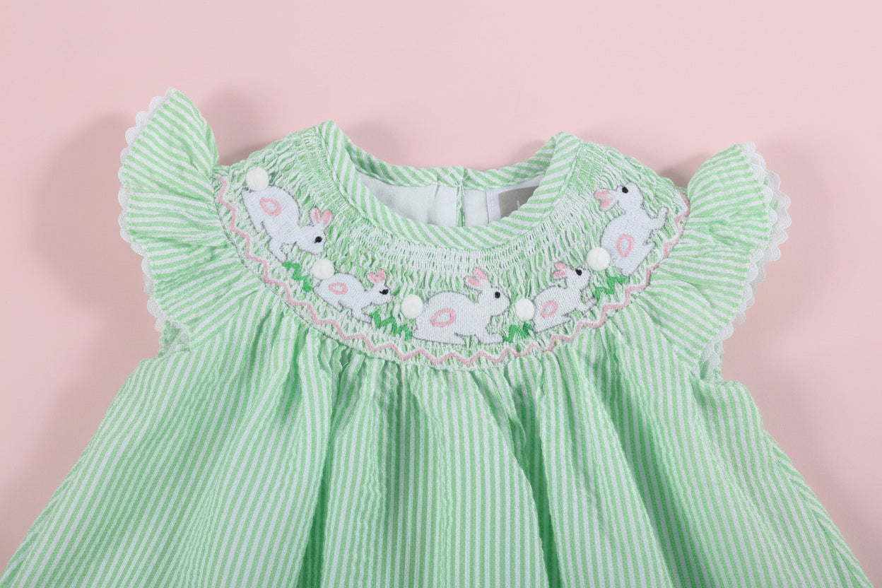 Green baby romper with embroidered bunny design on a pink background