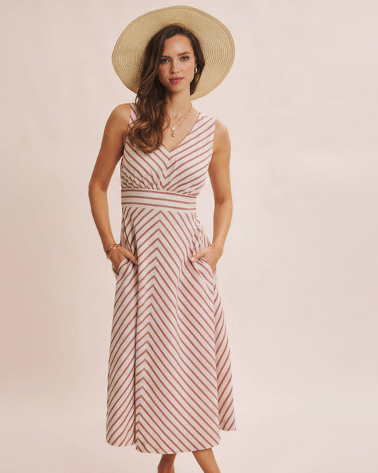 Woman wearing a striped dress and straw hat on a plain background